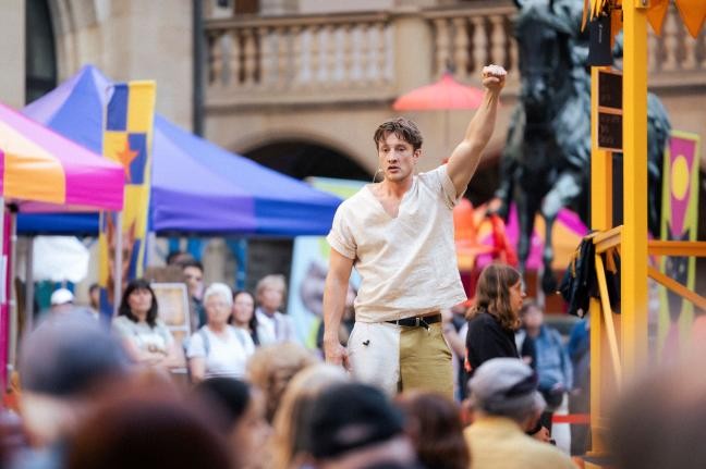 Im Theaterstück recht ein ärmlich gekleideter Mann die Faust in die Luft.