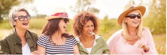 Vier lachende Frauen vor einer Wiese