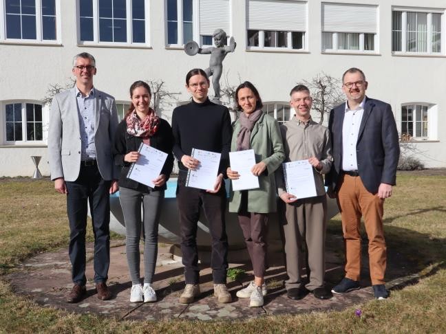 Fünf Absolventen, Landrat und Personalleiter stehen vor dem Landratsamt