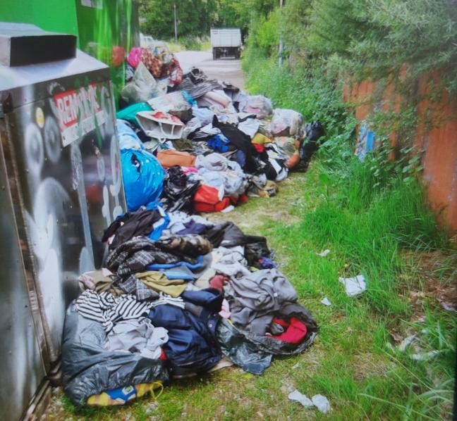 Altkleider liegen verstreut um die Altglas- und Sammelcontainer