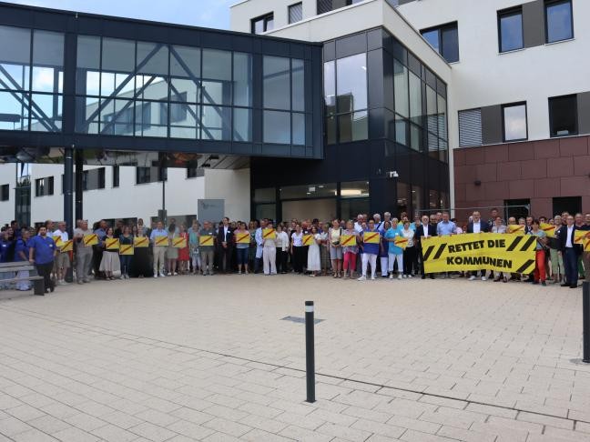 Teilnehmergruppe mit Plakaten und Banner vor dem Eingang des Klinikums 